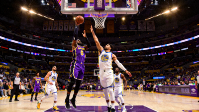 NBA季后赛直播画面，湖人队紫色球衣球员跳投，勇士队白色球衣球员封盖，篮球场馆内灯光璀璨